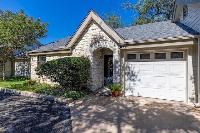 9226 Jollyville Rd Unit 191, Austin, TX 78759 - view of front of property with stone siding, asphalt driveway, an attached garage, and a shingled roof