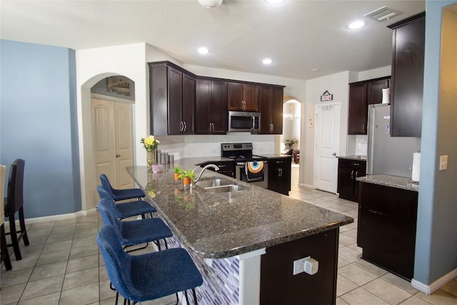 19108 Obed River Dr, Pflugerville, TX 78660 - kitchen with stainless steel appliances, arched walkways, light tile patterned flooring, a breakfast bar area, and decorative backsplash