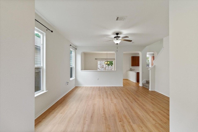 6729 Sunderland Trl, Austin, TX 78747 - unfurnished living room featuring a ceiling fan, light wood-type flooring, arched walkways, and baseboards