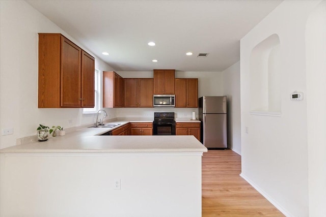 6729 Sunderland Trl, Austin, TX 78747 - kitchen featuring stainless steel appliances, a sink, light countertops, light wood-style flooring, and a peninsula