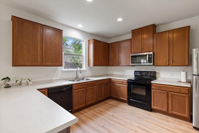 6729 Sunderland Trl, Austin, TX 78747 - kitchen featuring black appliances, a sink, light wood-type flooring, brown cabinetry, and recessed lighting