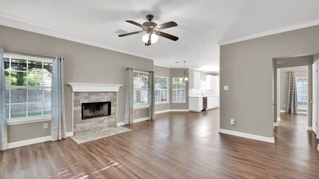 3504 Ashmere Loop SE, Round Rock, TX 78681 - unfurnished living room featuring crown molding, plenty of natural light, a tile fireplace, a ceiling fan, and dark wood-style floors