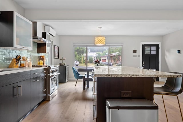 1707 Collier St, Austin, TX 78704 - kitchen featuring high end stove, light wood-style flooring, backsplash, a center island, and wall chimney range hood