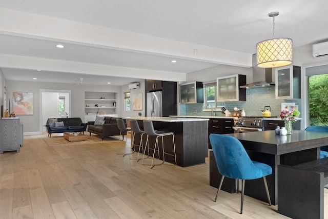 1707 Collier St, Austin, TX 78704 - kitchen featuring wall chimney range hood, appliances with stainless steel finishes, a kitchen bar, a kitchen island, and tasteful backsplash