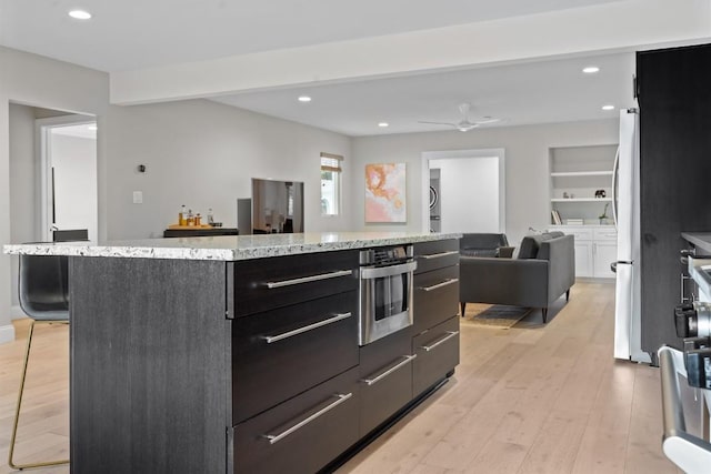 1707 Collier St, Austin, TX 78704 - kitchen featuring light wood-style flooring, open floor plan, freestanding refrigerator, dark cabinets, and recessed lighting