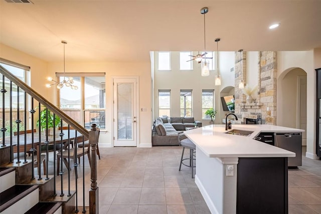 21305 Resource Rd, Pflugerville, TX 78660 - kitchen featuring arched walkways, stainless steel dishwasher, a sink, light tile patterned flooring, and an island with sink