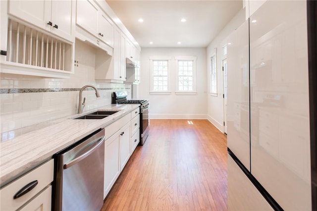 1206 W 22nd 1/2 St, Austin, TX 78705 - kitchen with appliances with stainless steel finishes, a sink, light wood-style floors, decorative backsplash, and white cabinetry