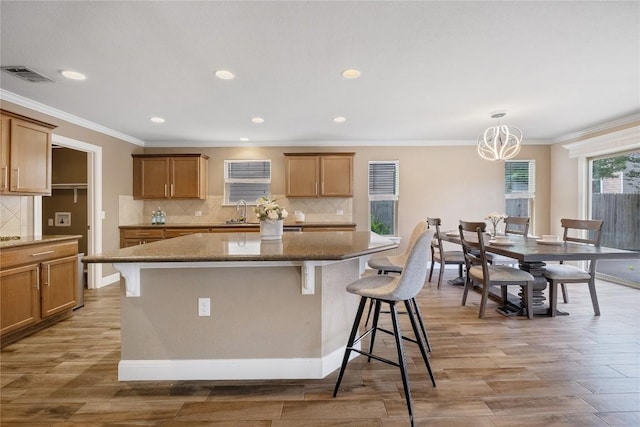 9008 Winter Haven Rd, Austin, TX 78747 - kitchen featuring a kitchen breakfast bar, a sink, dark stone countertops, decorative backsplash, and ornamental molding
