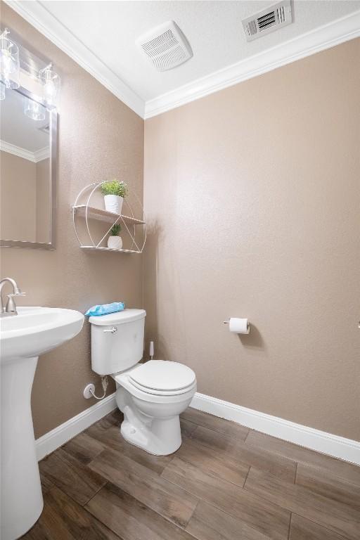 9008 Winter Haven Rd, Austin, TX 78747 - half bathroom with toilet, crown molding, wood finished floors, baseboards, and a sink