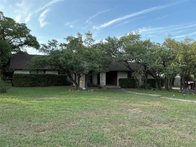 319 Fawnridge St, Georgetown, TX 78628 - view of property hidden behind natural elements with a front yard, stone siding, and a shingled roof