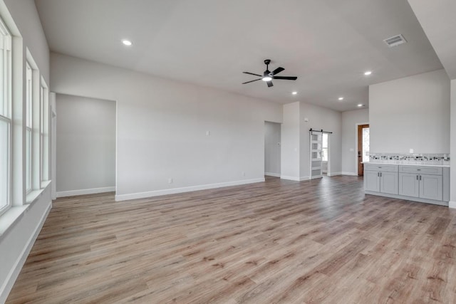 203 Alonzo Dr, Del Valle, TX 78617 - unfurnished living room featuring a ceiling fan, a barn door, light wood finished floors, and recessed lighting
