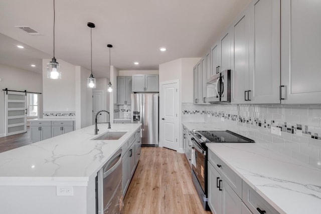 203 Alonzo Dr, Del Valle, TX 78617 - kitchen featuring appliances with stainless steel finishes, light wood-type flooring, decorative backsplash, gray cabinetry, and recessed lighting
