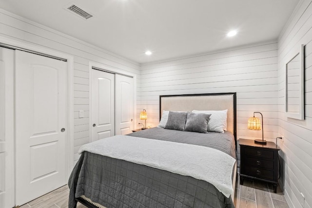 810 River Rd, Wimberley, TX 78676 - bedroom featuring two closets, light wood finished floors, wood walls, and recessed lighting