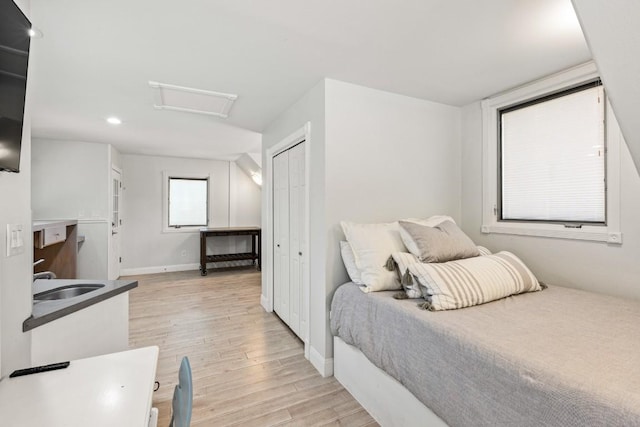 810 River Rd, Wimberley, TX 78676 - bedroom with light wood-style flooring, attic access, a sink, recessed lighting, and baseboards