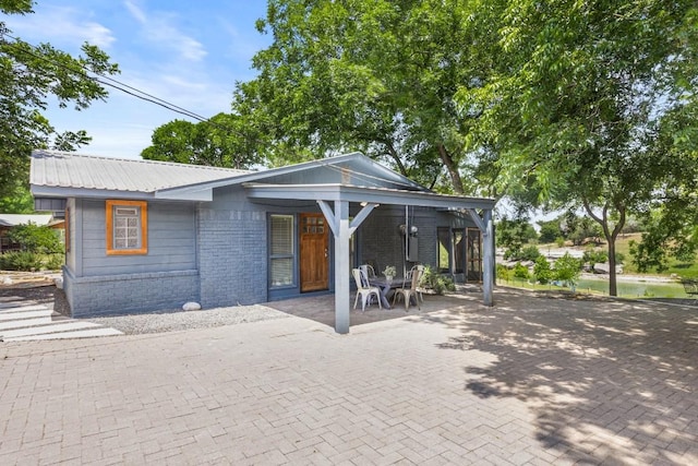 810 River Rd, Wimberley, TX 78676 - view of front facade featuring metal roof, a patio area, and brick siding