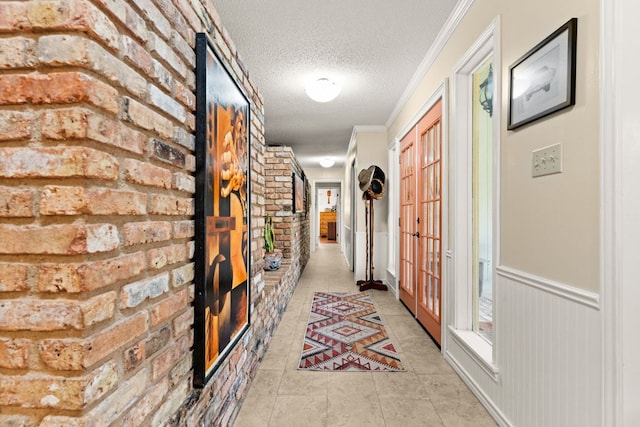 112 Skipcha Trl, Lampasas, TX 76550 - hallway with a textured ceiling, brick wall, ornamental molding, french doors, and light tile patterned flooring