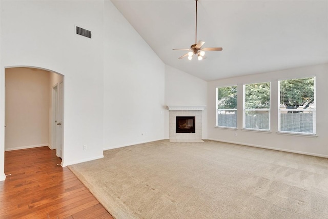 2225 Lou John St, Austin, TX 78727 - unfurnished living room with high vaulted ceiling, arched walkways, a ceiling fan, a tiled fireplace, and baseboards