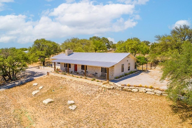 25404 Hamilton Pool Rd, Round Mountain, TX 78663 - ranch-style home featuring a chimney, metal roof, stone siding, covered porch, and a standing seam roof