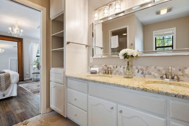 25404 Hamilton Pool Rd, Round Mountain, TX 78663 - full bath with a chandelier, double vanity, connected bathroom, and wood finished floors