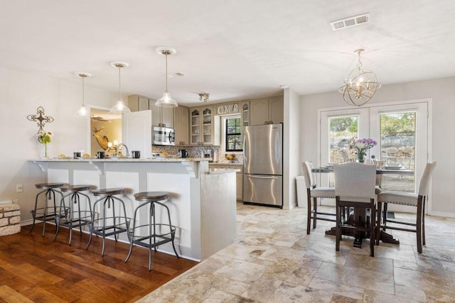 25404 Hamilton Pool Rd, Round Mountain, TX 78663 - kitchen with stainless steel appliances, a peninsula, a kitchen bar, glass insert cabinets, and a chandelier