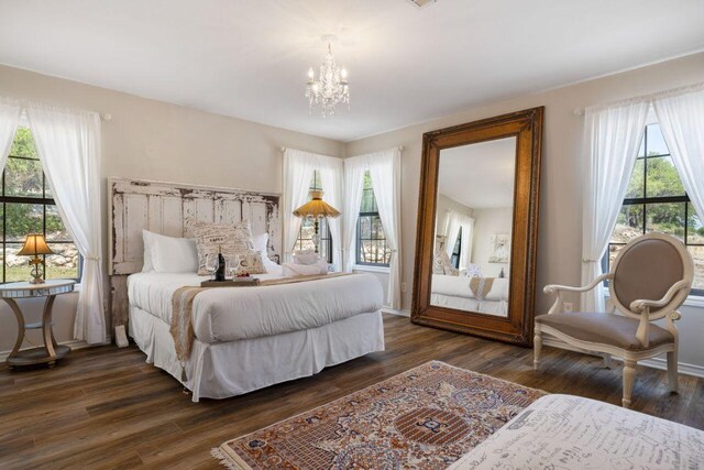 25404 Hamilton Pool Rd, Round Mountain, TX 78663 - bedroom with a chandelier, multiple windows, and dark wood-type flooring