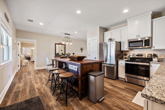 25404 Hamilton Pool Rd, Round Mountain, TX 78663 - kitchen with appliances with stainless steel finishes, dark wood-style flooring, white cabinetry, a kitchen island, and recessed lighting