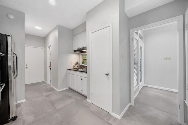 8316 Greenslope Dr Unit A, Austin, TX 78759 - kitchen featuring finished concrete flooring, freestanding refrigerator, white cabinets, baseboards, and under cabinet range hood