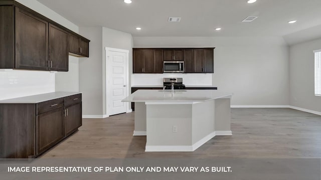 362 Barron Estate Dr, Lockhart, TX 78644 - kitchen with stainless steel appliances, light wood-style flooring, dark brown cabinetry, baseboards, and an island with sink