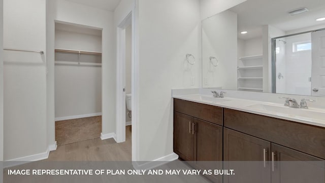 362 Barron Estate Dr, Lockhart, TX 78644 - bathroom featuring a walk in closet, a stall shower, wood finished floors, double vanity, and toilet