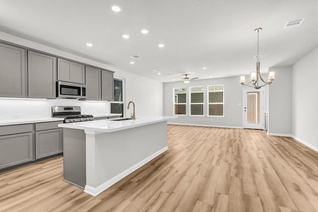 1621 Coral Sunrise Aly, Leander, TX 78641 - kitchen with stainless steel appliances, gray cabinetry, a sink, light wood finished floors, and recessed lighting