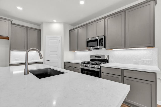 1621 Coral Sunrise Aly, Leander, TX 78641 - kitchen with stainless steel appliances, gray cabinets, a sink, backsplash, and recessed lighting