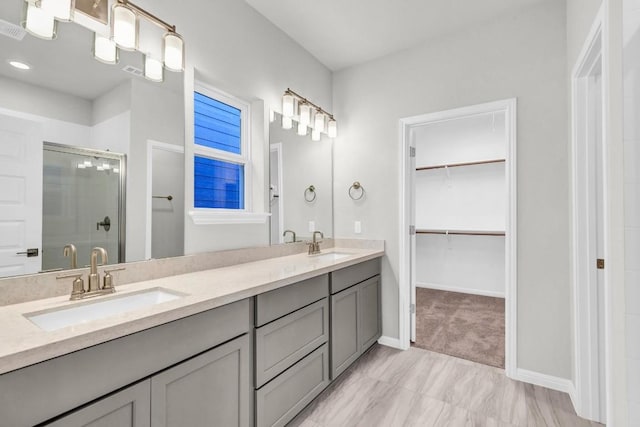 1621 Coral Sunrise Aly, Leander, TX 78641 - bathroom with a shower stall, a walk in closet, double vanity, and baseboards