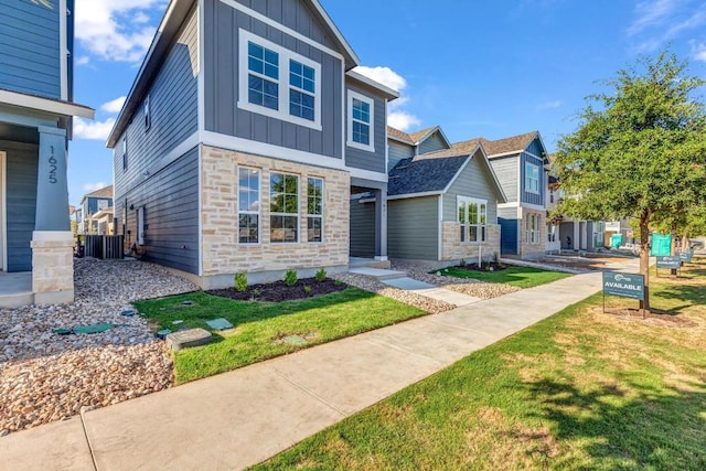 1621 Coral Sunrise Aly, Leander, TX 78641 - view of front of house featuring board and batten siding, stone siding, and a front lawn