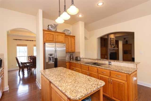 1367 Indian Pass, Salado, TX 76571 - kitchen with stainless steel refrigerator with ice dispenser, a center island, arched walkways, baseboards, and light stone countertops