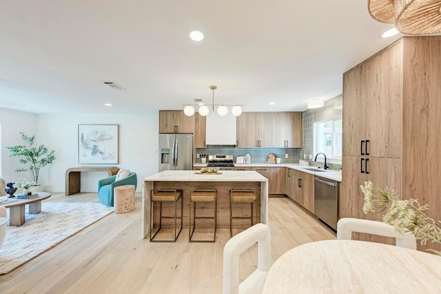 1314 Ridgemont Dr, Austin, TX 78723 - kitchen with appliances with stainless steel finishes, a sink, a kitchen island, a kitchen breakfast bar, and backsplash