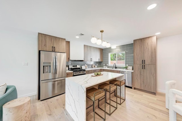 1314 Ridgemont Dr, Austin, TX 78723 - kitchen featuring appliances with stainless steel finishes, a sink, a kitchen bar, light wood-style flooring, and recessed lighting