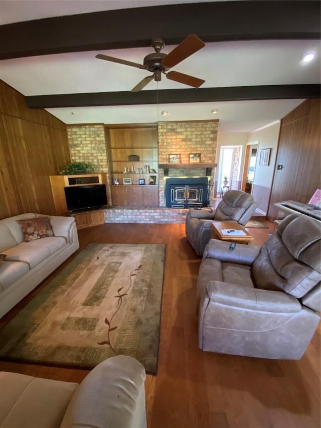 140 Oakridge Rd, Georgetown, TX 78628 - living area with a brick fireplace, wood walls, beamed ceiling, a ceiling fan, and wood finished floors