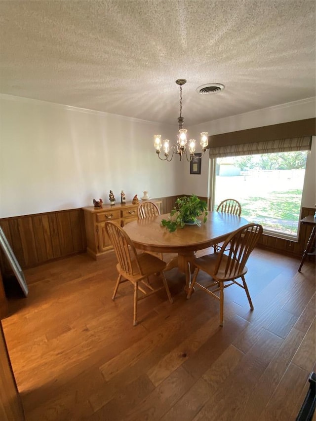 140 Oakridge Rd, Georgetown, TX 78628 - dining space featuring wood finished floors, a textured ceiling, a chandelier, a wainscoted wall, and ornamental molding