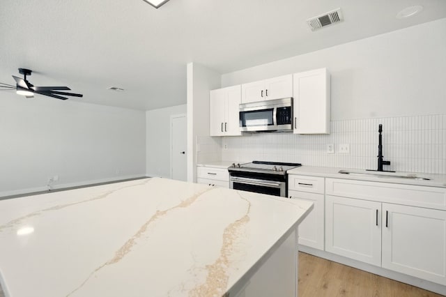 179 Pimlico, Kyle, TX 78640 - kitchen featuring appliances with stainless steel finishes, a sink, white cabinets, a ceiling fan, and backsplash