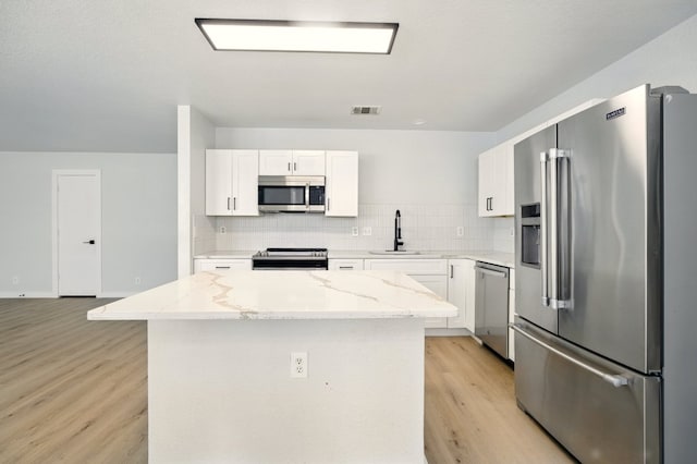 179 Pimlico, Kyle, TX 78640 - kitchen with appliances with stainless steel finishes, a sink, decorative backsplash, light wood-style floors, and light stone counters