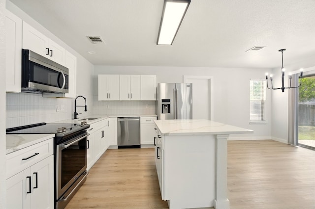 179 Pimlico, Kyle, TX 78640 - kitchen featuring appliances with stainless steel finishes, a sink, light wood-type flooring, and a kitchen island