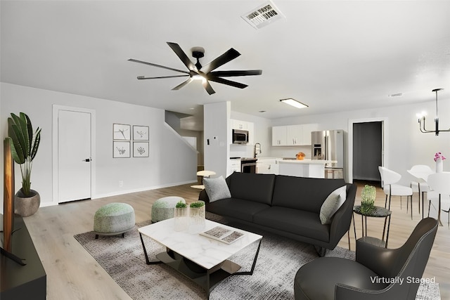 179 Pimlico, Kyle, TX 78640 - living room with light wood finished floors, ceiling fan, a chandelier, and baseboards