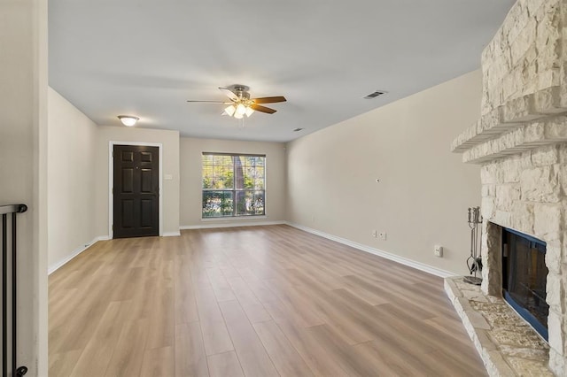 2511 Jacqueline Dr, Leander, TX 78641 - unfurnished living room with ceiling fan, a stone fireplace, light wood-style floors, and baseboards