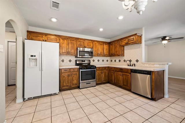 2511 Jacqueline Dr, Leander, TX 78641 - kitchen featuring stainless steel appliances, light countertops, decorative backsplash, a sink, and arched walkways