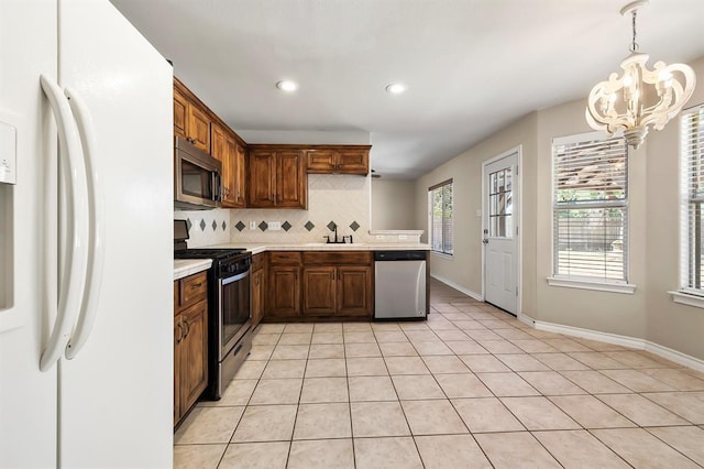 2511 Jacqueline Dr, Leander, TX 78641 - kitchen with appliances with stainless steel finishes, a chandelier, light countertops, decorative backsplash, and light tile patterned floors