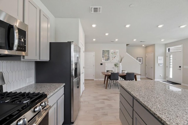 9015 Cattle Baron Path Unit 404, Austin, TX 78747 - kitchen with stainless steel appliances, tasteful backsplash, light stone countertops, gray cabinetry, and recessed lighting