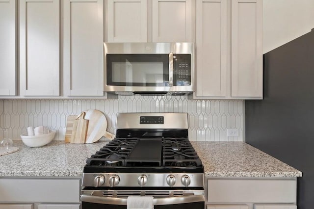 9015 Cattle Baron Path Unit 404, Austin, TX 78747 - kitchen with stainless steel appliances, backsplash, and light stone counters