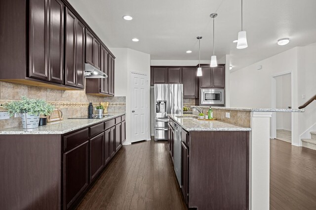 423 Sierra Mar Loop, Leander, TX 78641 - kitchen featuring appliances with stainless steel finishes, under cabinet range hood, dark brown cabinetry, dark wood-style flooring, and recessed lighting