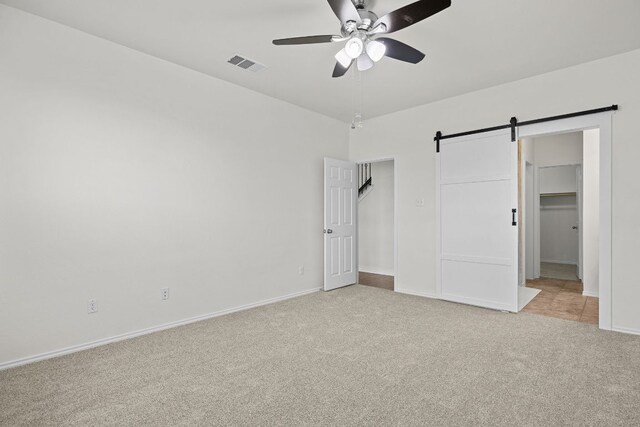 423 Sierra Mar Loop, Leander, TX 78641 - unfurnished bedroom with light carpet, a spacious closet, a barn door, ceiling fan, and a closet