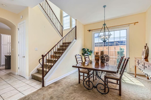 3824 Gaines Ct, Austin, TX 78735 - dining room with a chandelier, arched walkways, stairs, light colored carpet, and light tile patterned floors
